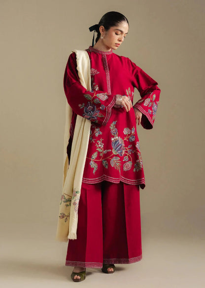 Woman wearing a red embroidered outfit with a beige scarf against a beige background