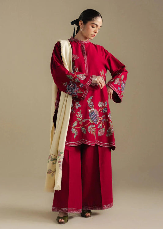 Woman wearing a red embroidered outfit with a beige scarf against a beige background