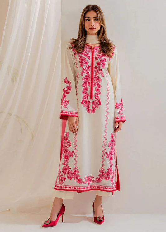 Woman wearing a white and pink embroidered traditional outfit against a white background