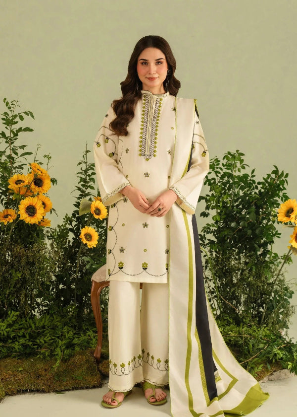 Woman in a cream embroidered outfit standing in front of sunflowers and greenery